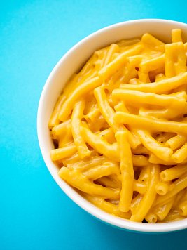Demi-bol de Mac and Cheese au cheddar sur fond bleu